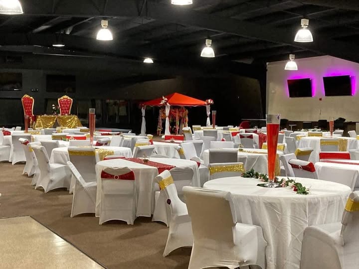 Phillips Event Center elegantly decorated banquet hall with white chair covers, gold accents, and red centerpieces